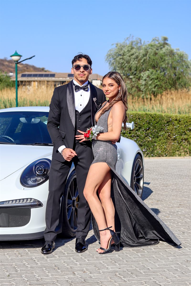 Portrait of a couple in formal dress leaning against a white Porsche 911