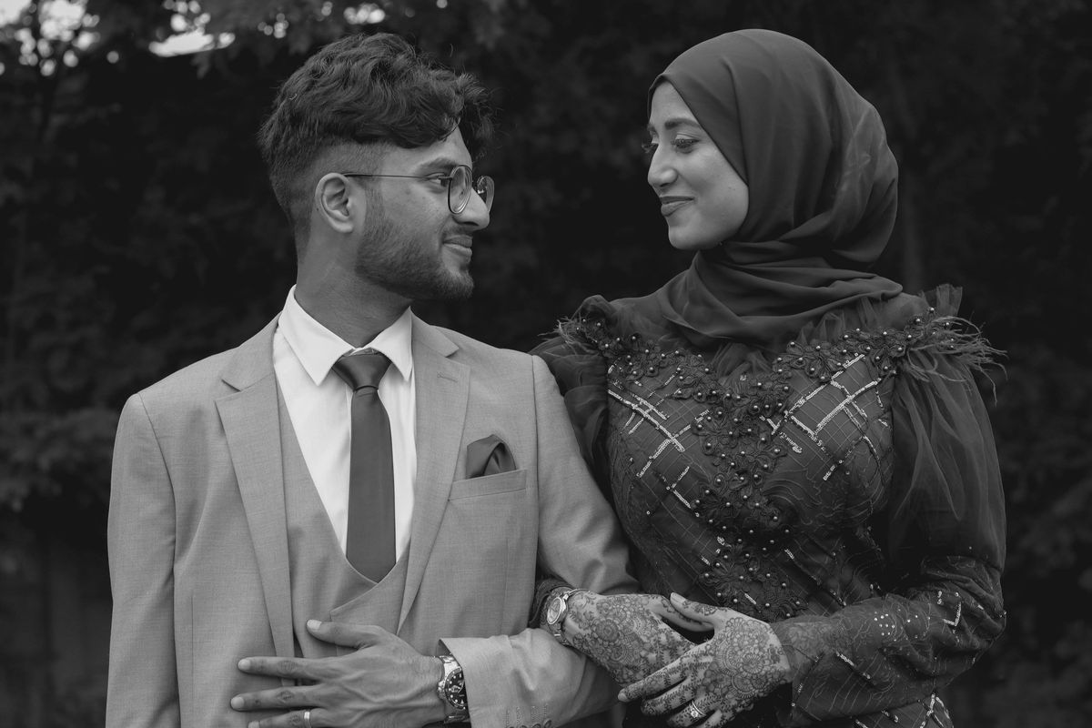 Black and white portrait of a couple standing close, hands clasped
